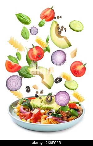 Plate with delicious pasta salad and falling ingredients on white background Stock Photo