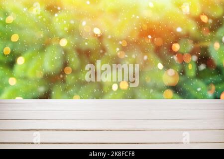 Light wooden table against blurred background with snow and glowing Christmas lights Stock Photo