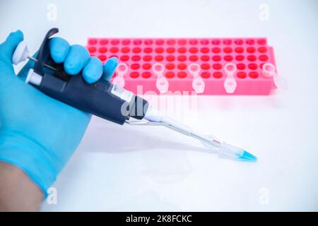 Scientist holding micropipette by rack on table in laboratory Stock Photo
