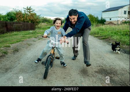 Happy father teaching son to ride bicycle Stock Photo