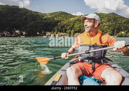 Happy man having fun kayaking at lake on sunny day Stock Photo