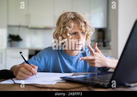 Boy counting through fingers looking at laptop Stock Photo