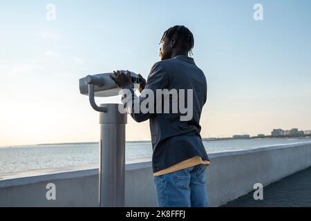 Businessman in front of coin-operated binoculars on footpath Stock Photo