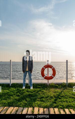 Businessman standing by lifeguard ring on footpath Stock Photo