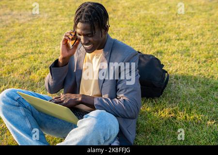 Happy businessman using laptop and talking on mobile phone Stock Photo