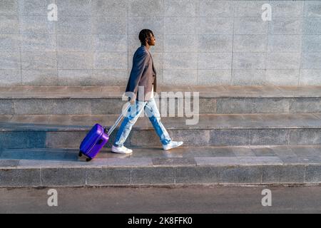 Smiling businessman with suitcase walking on step Stock Photo