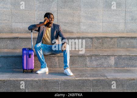 Smiling businessman talking over mobile phone sitting on steps Stock Photo