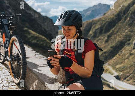 Cyclist wearing helmet using smart phone by bicycle Stock Photo