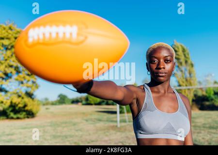 Sportswoman showing ball on sunny day Stock Photo