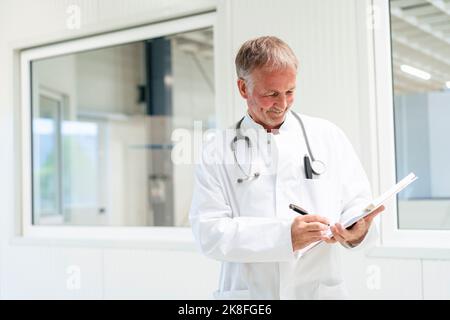 Smiling doctor writing on document at clinic Stock Photo