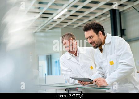 Happy engineer with colleague using tablet PC at industry Stock Photo