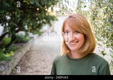 Happy mature woman in redhead sitting in garden Stock Photo