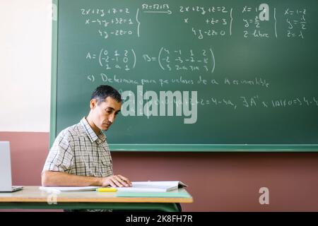 Math teacher reading book in classroom Stock Photo