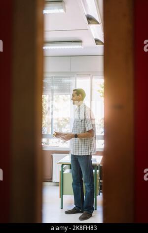 Professor teaching in classroom seen through doorway Stock Photo