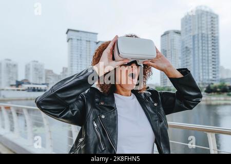 Shocked woman using VR glasses in city Stock Photo