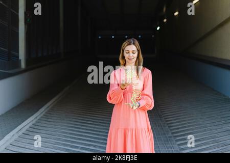 Smiling woman playing with coil spring toy Stock Photo
