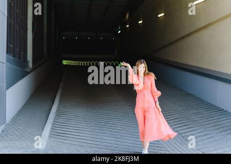 Playful woman spinning metal coil toy on footpath Stock Photo