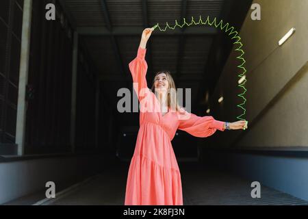 Playful woman playing with metal coil toy on footpath Stock Photo