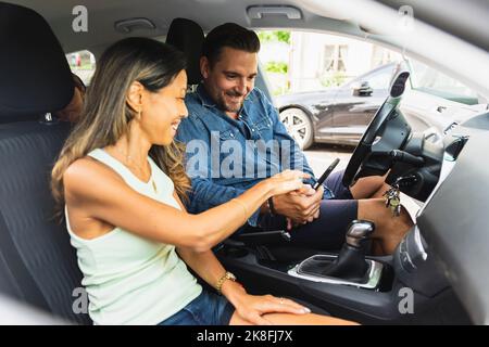 Couple using smart phone sitting in car Stock Photo