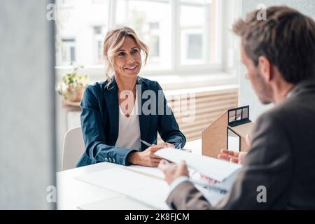Real estate agent and client discussing with each other at office Stock Photo