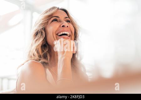 Happy mature woman with hand on chin Stock Photo