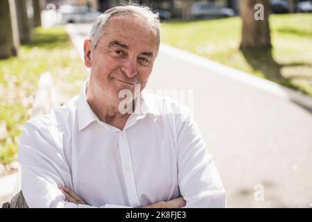 Smiling senior man with arms crossed on sunny day Stock Photo