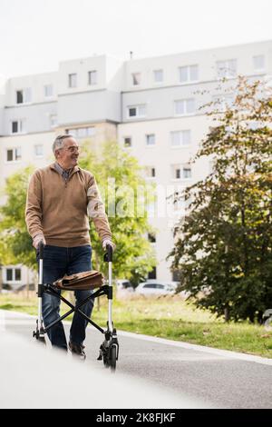 Senior man with mobility walker walking on footpath Stock Photo