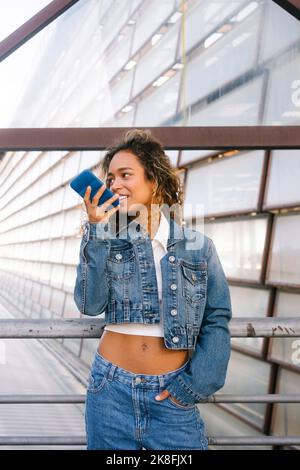 Young woman in denim jacket sending voicemail though smart phone Stock Photo