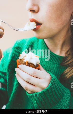 Woman eating icing on cupcake with fork Stock Photo