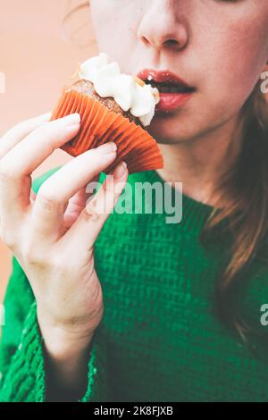Woman eating cupcake with icing Stock Photo