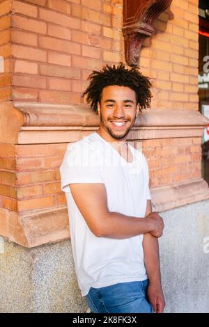 Smiling young man leaning on wall Stock Photo