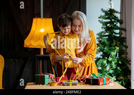 Mother and son cutting ribbon to tie gift Stock Photo