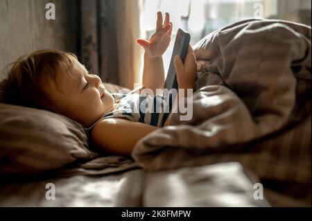 Baby boy using mobile phone in bed at home Stock Photo