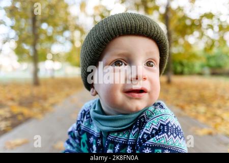 Cute boy with brown eyes wearing knit hat in park Stock Photo