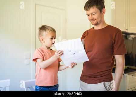 Son showing drawing to father at home Stock Photo