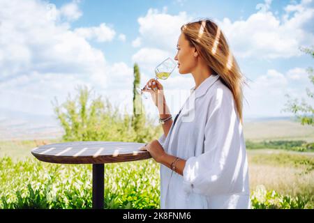 Woman drinking white wine standing at table Stock Photo