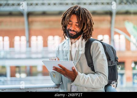 Smiling businessman using tablet PC at central station Stock Photo