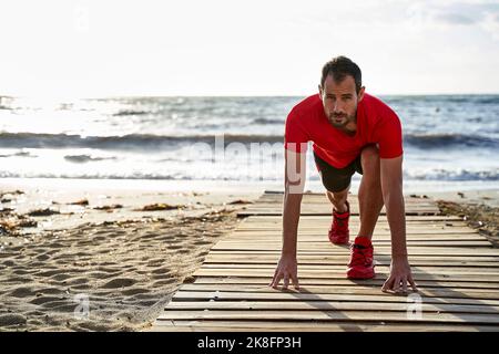 Man doing stretching exercise on boardwalk Stock Photo