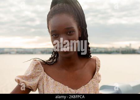 Smiling young woman standing by railing in front of river Stock Photo