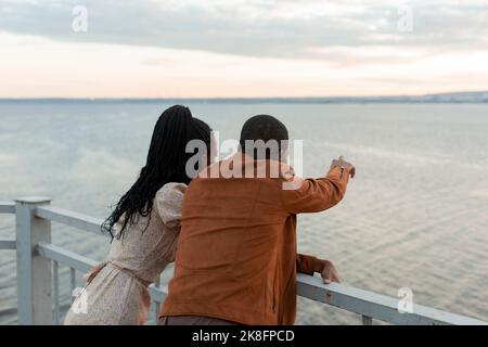 Young couple standing by railing looking at river Stock Photo