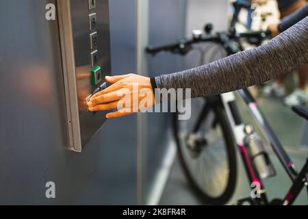 Woman hand pushing button of elevator with bicycle Stock Photo