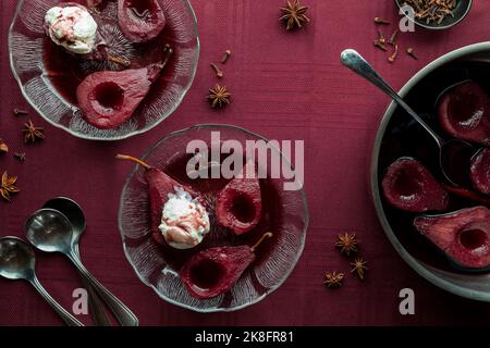 Servings of poached pears in spiced red wine sauce, ready for eating. Stock Photo