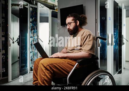 Technician with disability working on laptop in server room Stock Photo