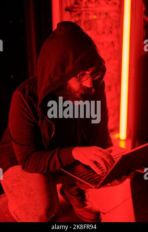 Hacker using laptop crouching in data center Stock Photo
