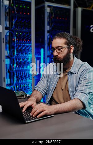IT engineer using laptop at desk in control room Stock Photo