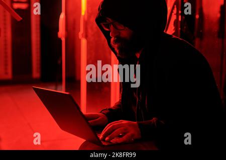 Hacker using laptop for malicious purpose in data center Stock Photo