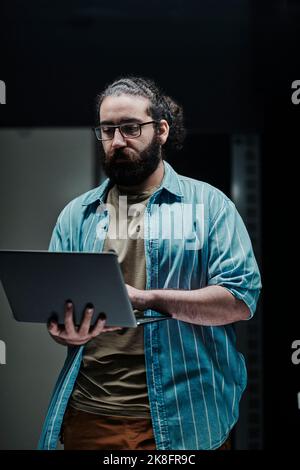 IT technician working on laptop standing in server room Stock Photo
