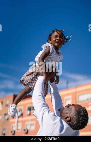 Father lifting daughter in front of building Stock Photo