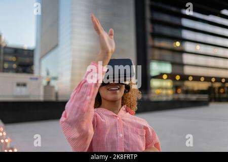 Smiling woman gesturing and using virtual reality simulator Stock Photo
