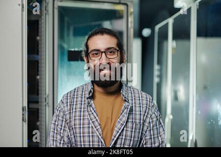Happy computer programmer with beard wearing eyeglasses in server room Stock Photo